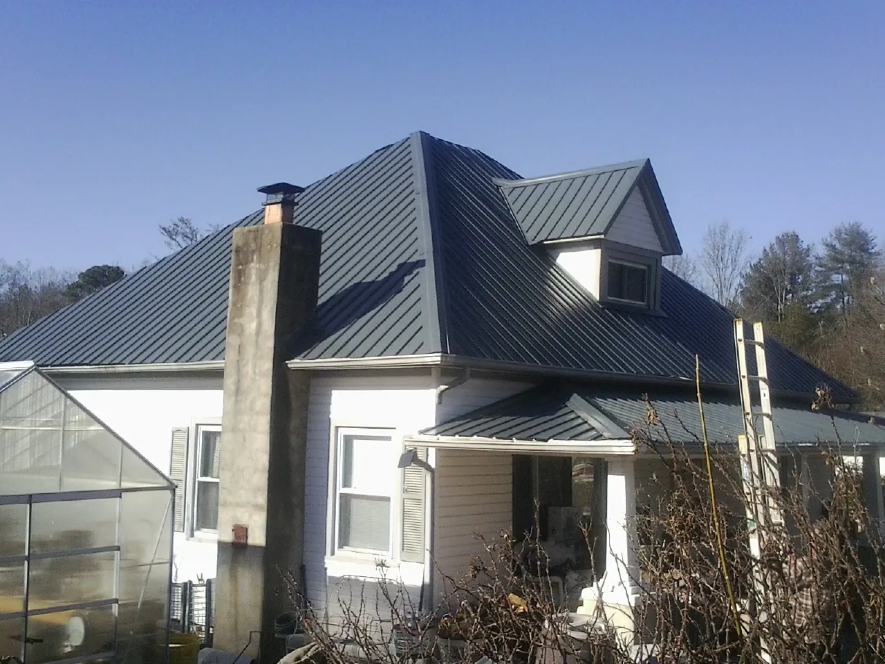 Dark blue standing seam metal roof on a white farmhouse with dormer — Slate & Tile Roof Repair by Roofing Brothers in Sartell