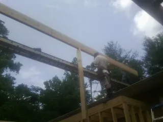 Carpenter setting a ridge beam over a new addition frame — Ice Dam Removal by Roofing Brothers in Sartell