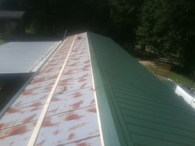 Old rusted panels beside newly installed green metal roofing — Wind Damage Roof Repair by Roofing Brothers in Sartell