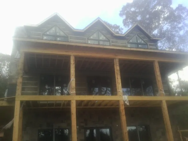 Dormers and porch framing on a large log home under construction — Roof Coating work by our crew in Sartell