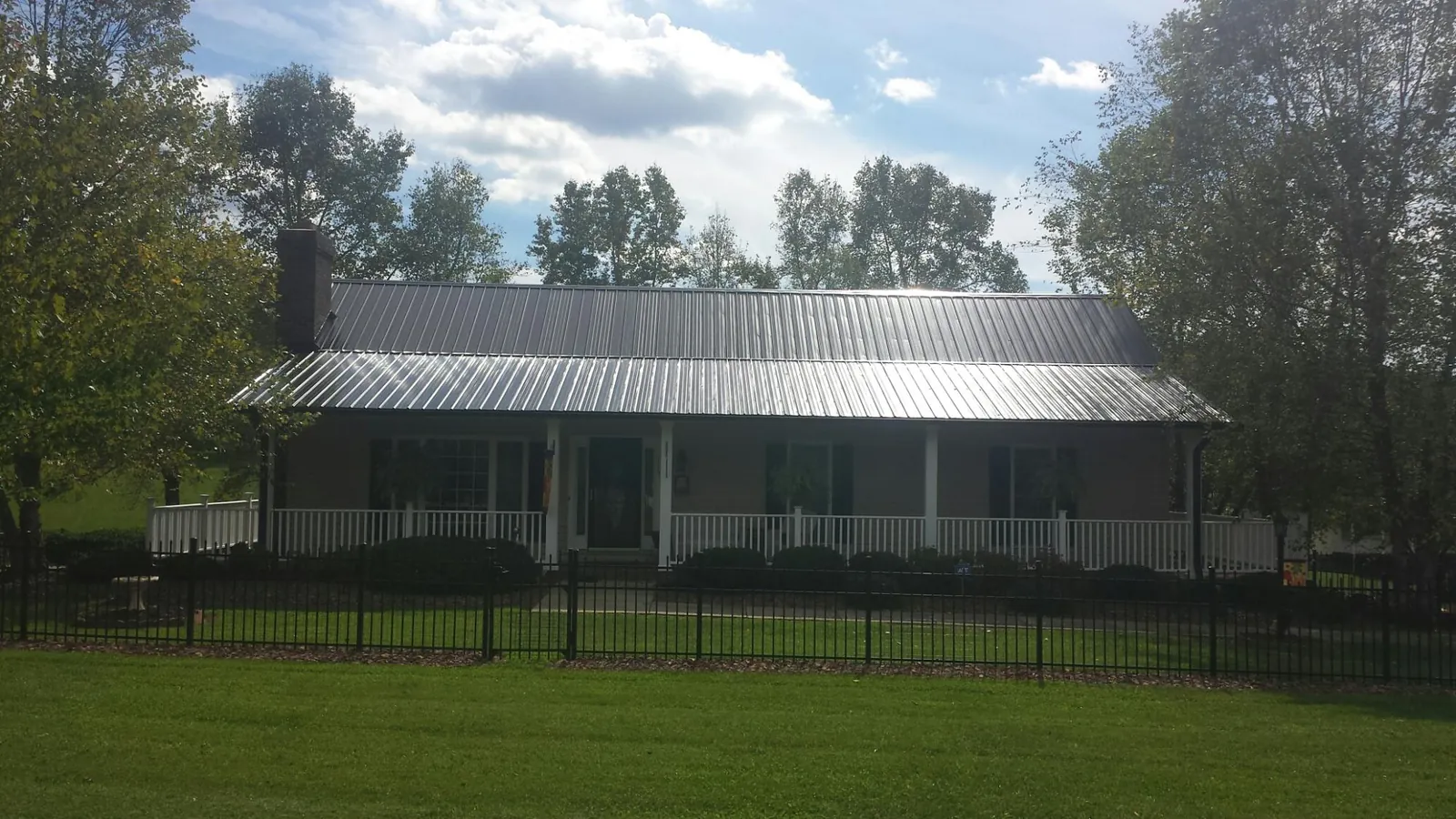 Gray metal roof on a brick ranch with a full width front porch — Gutter Guard Installation work by our crew in Sartell