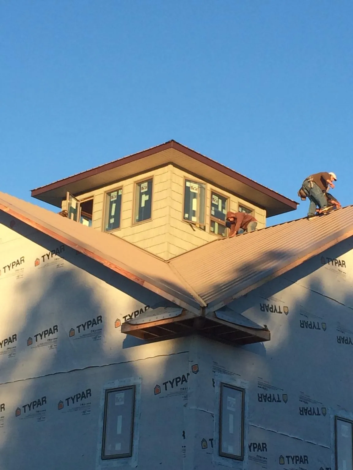 Roofers working around a rooftop cupola on a new metal roof at sunset — Roof Waterproofing in Sartell by Roofing Brothers